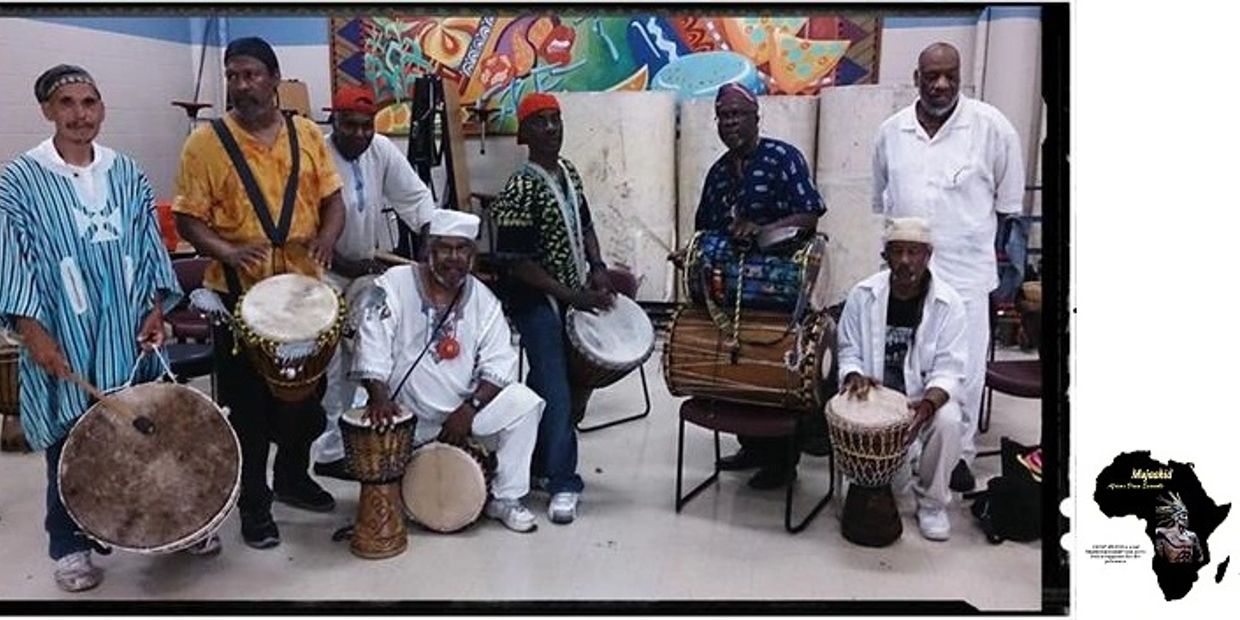 Group of men playing traditional African drums in a colorful room.
