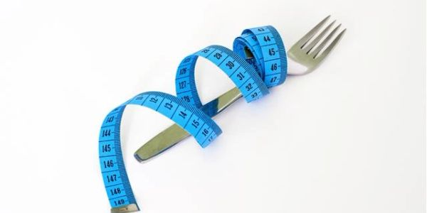 A fork wrapped with a blue measuring tape on a white background.